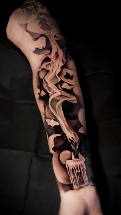 Black and grey realism candle and smoke tattoo on a forearm