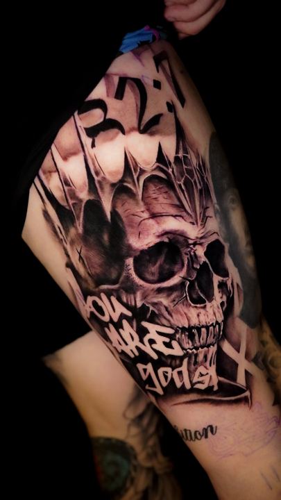 Black and grey realism skull and lettering tattoo on an arm