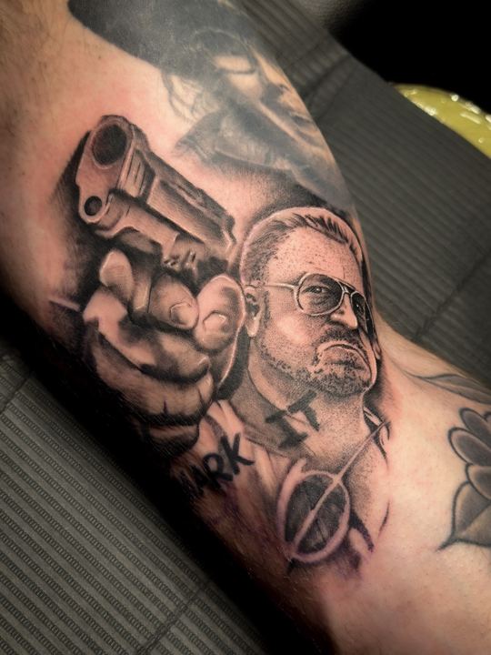 Black and grey realism portrait and revolver tattoo on an arm