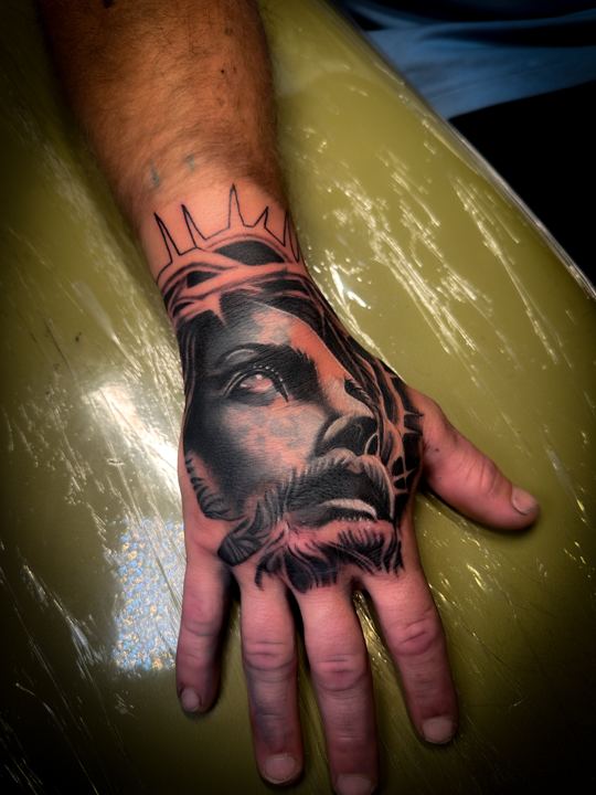 Black and grey realism portrait with a crown of thorns on the back of a hand