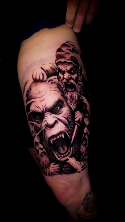 Black and grey realism snarling ape and gnomes tattoo on an arm