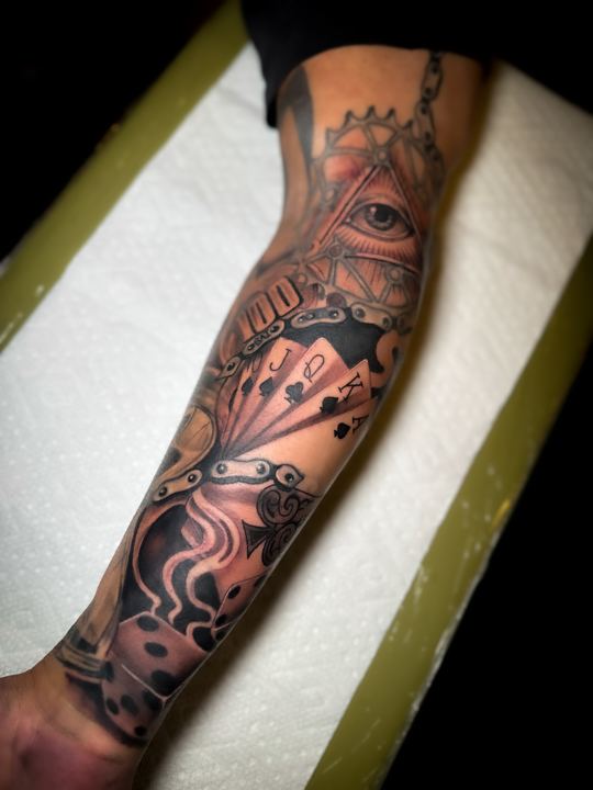 Black and grey realism sleeve with an eye, playing cards and dice