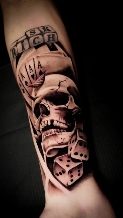 Black and grey realism skull, aces and dice tattoo on a forearm
